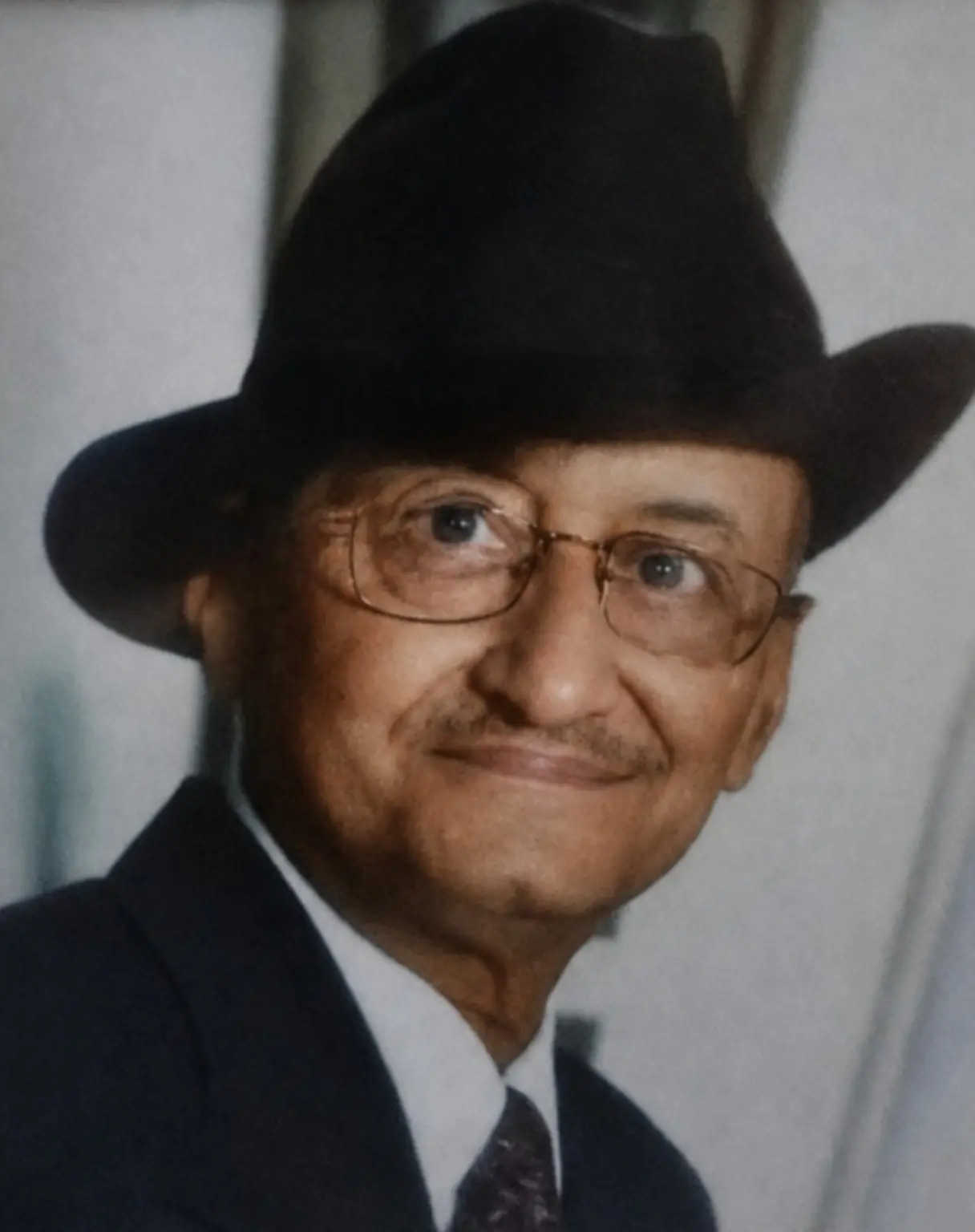 Portrait of Rabboo Joshi smiling in his black hat
