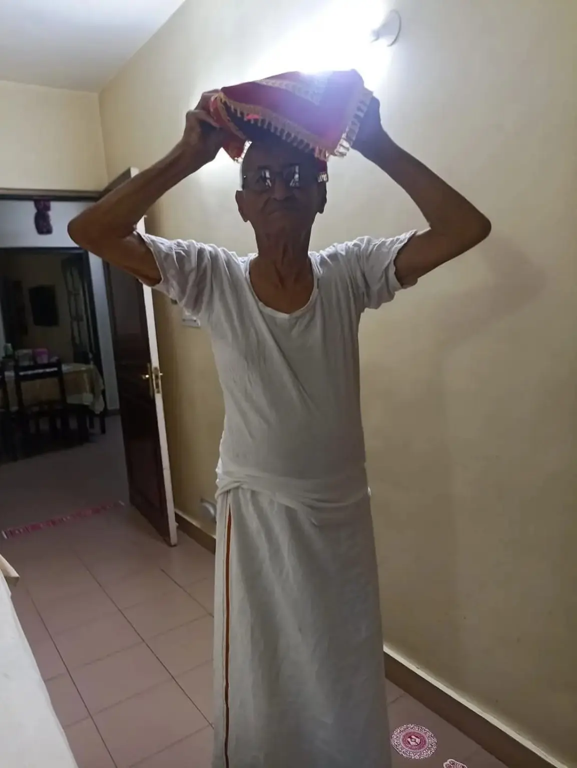 Rabboo Joshi carrying covered malpua prasad on his head at home in Delhi