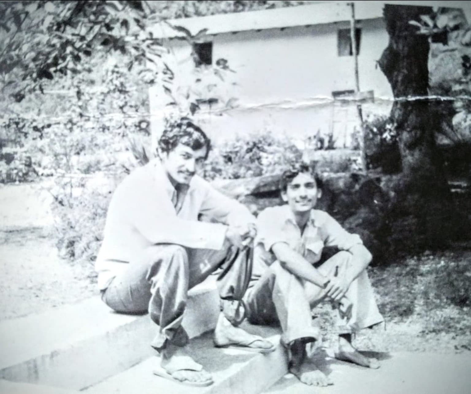 Black-and-white photograph of Sumati’s father as a young man seated with his cousin near the yagya shala at Kainchi
