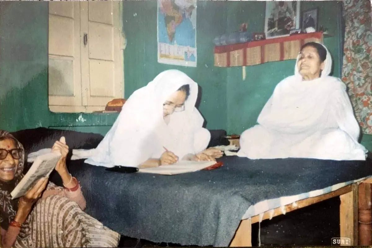Ma and Choti Ma seated on a bed while Sumati’s grandmother sits on the floor beside them