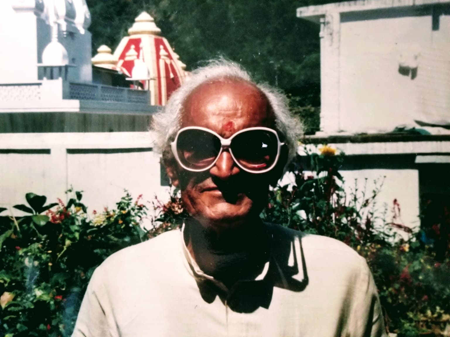 Shri Hem Chandra Joshi, known as Hem Da, wearing large sunglasses in the garden at Kainchi