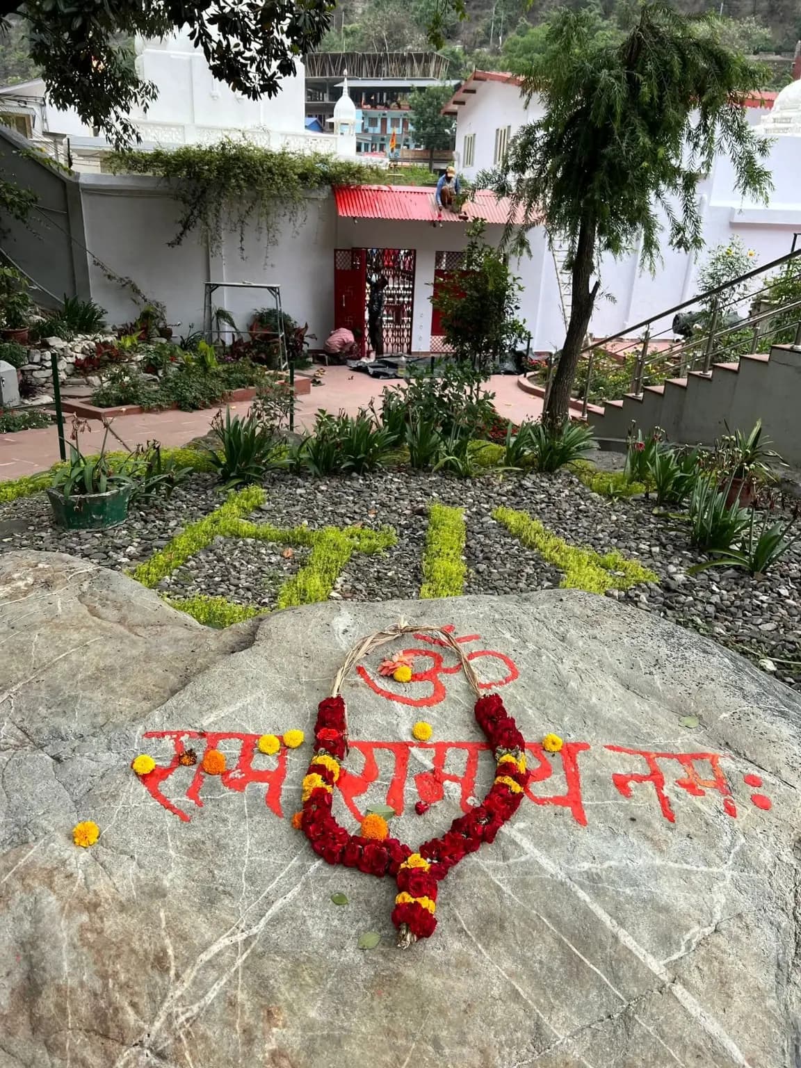 Garlanded shila at Kainchi marked with Om and Ram, remembered as the place where Maharajji used to sit