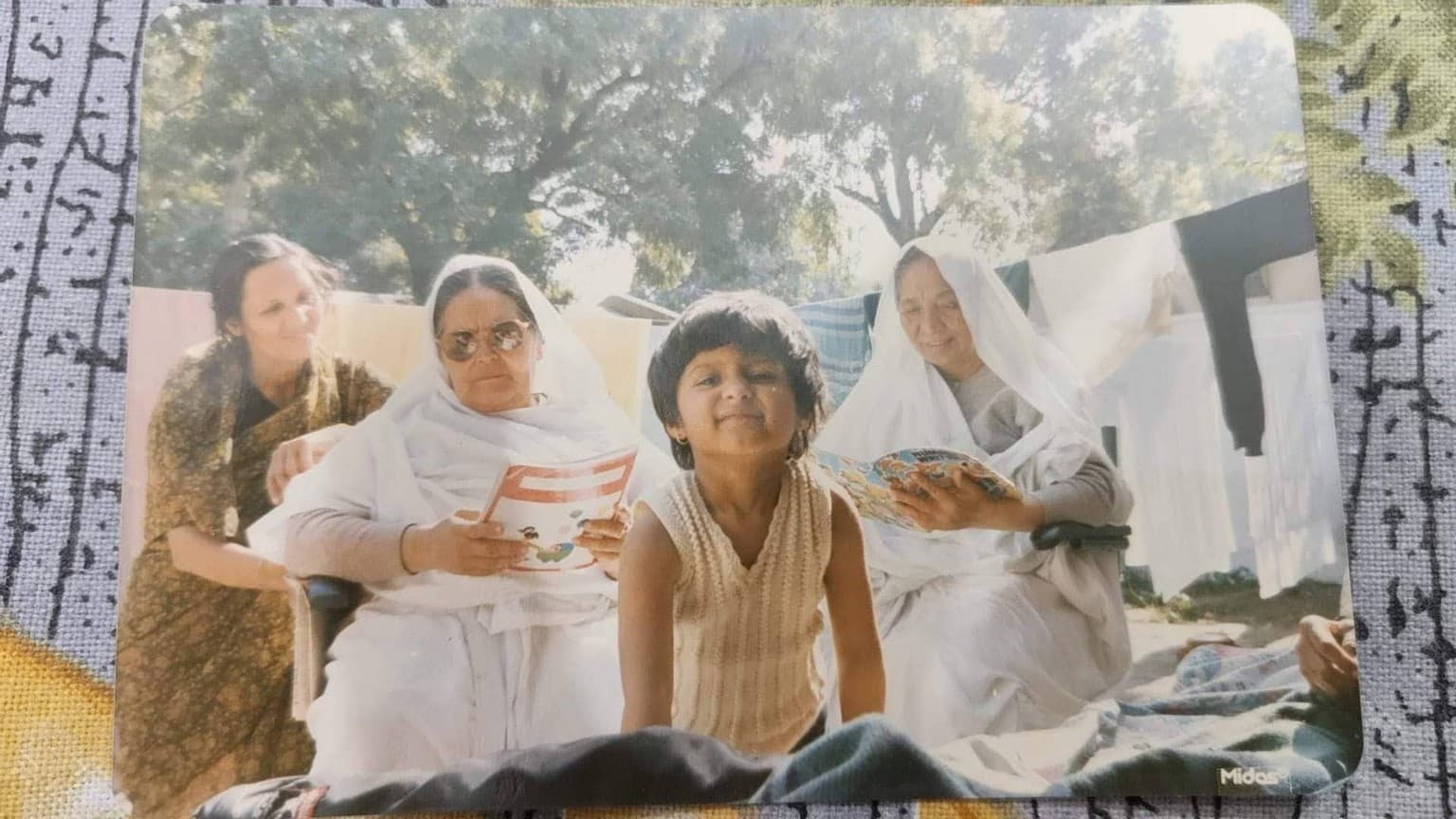 Ma seated outdoors reading at Sumati’s family home in Bareilly, with Sumati’s sister standing in front