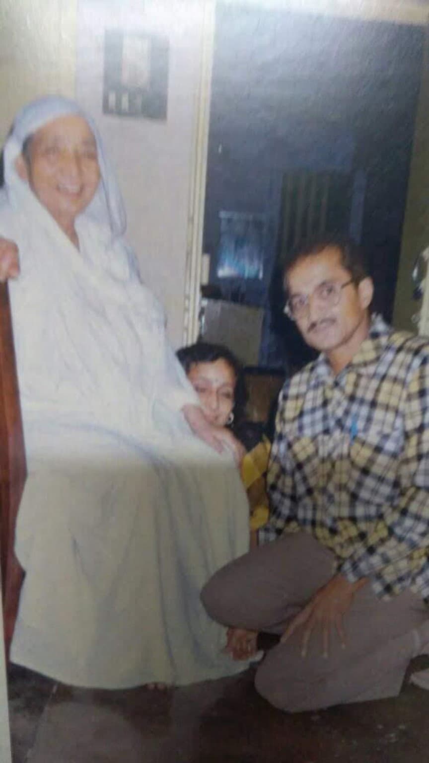 Ma seated on a chair, with Sumati’s mother peeking from behind and her father seated beside Ma