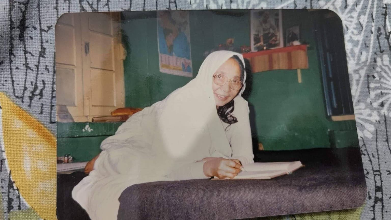 Ma in white, wearing glasses and writing in a notebook in an earlier family photograph